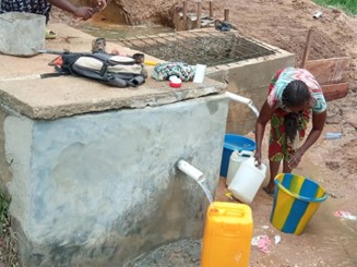 Photo of woman getting water at a well.